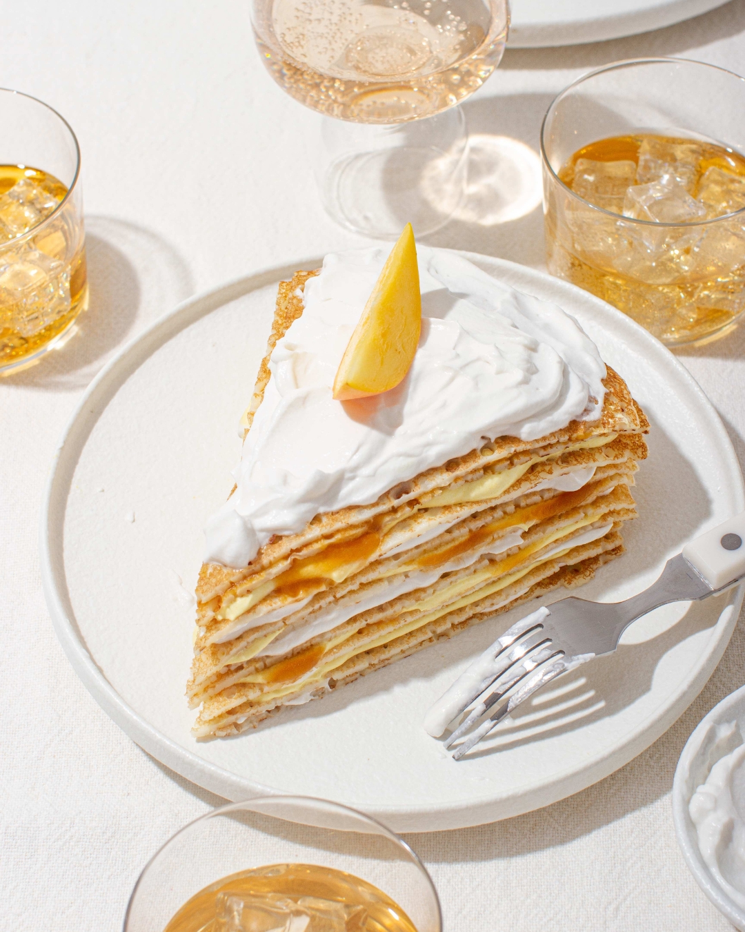 Mango Crepe Cake stacked on a plate and decorated with mango and whipped coconut cream